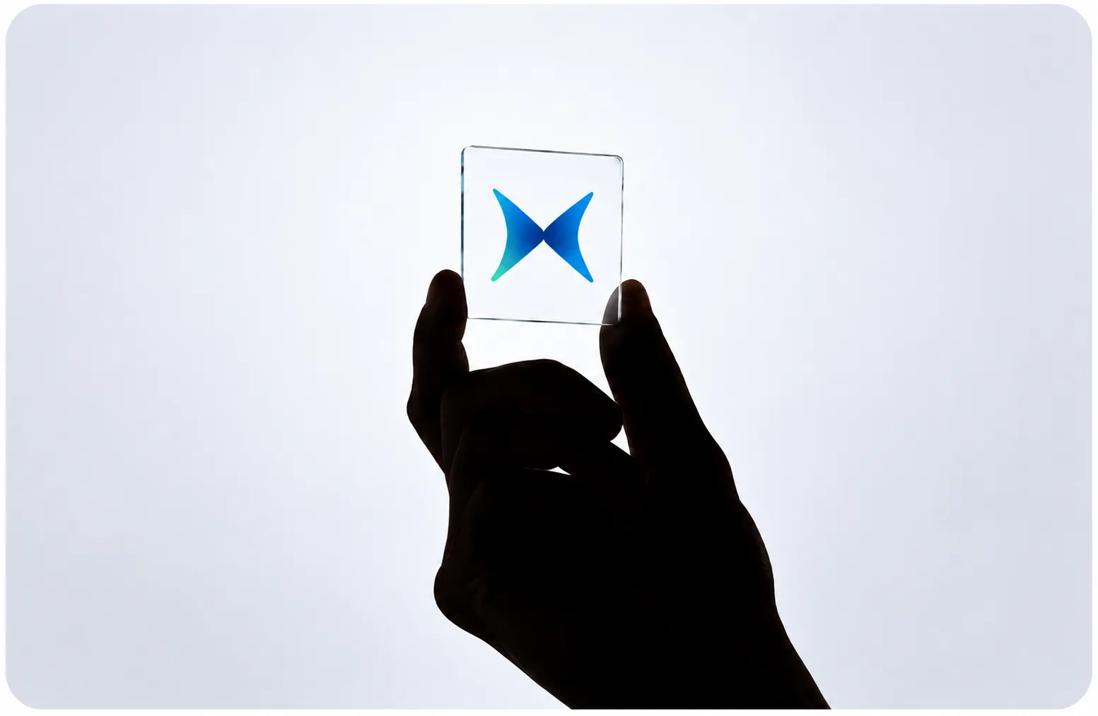 A hand holding up a glass tile with the Modular butterfly against a bright backdrop.